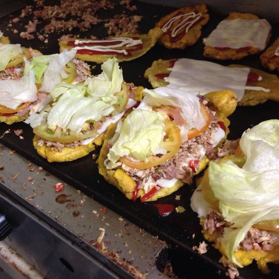 Patacón pisao topped with shredded cheese